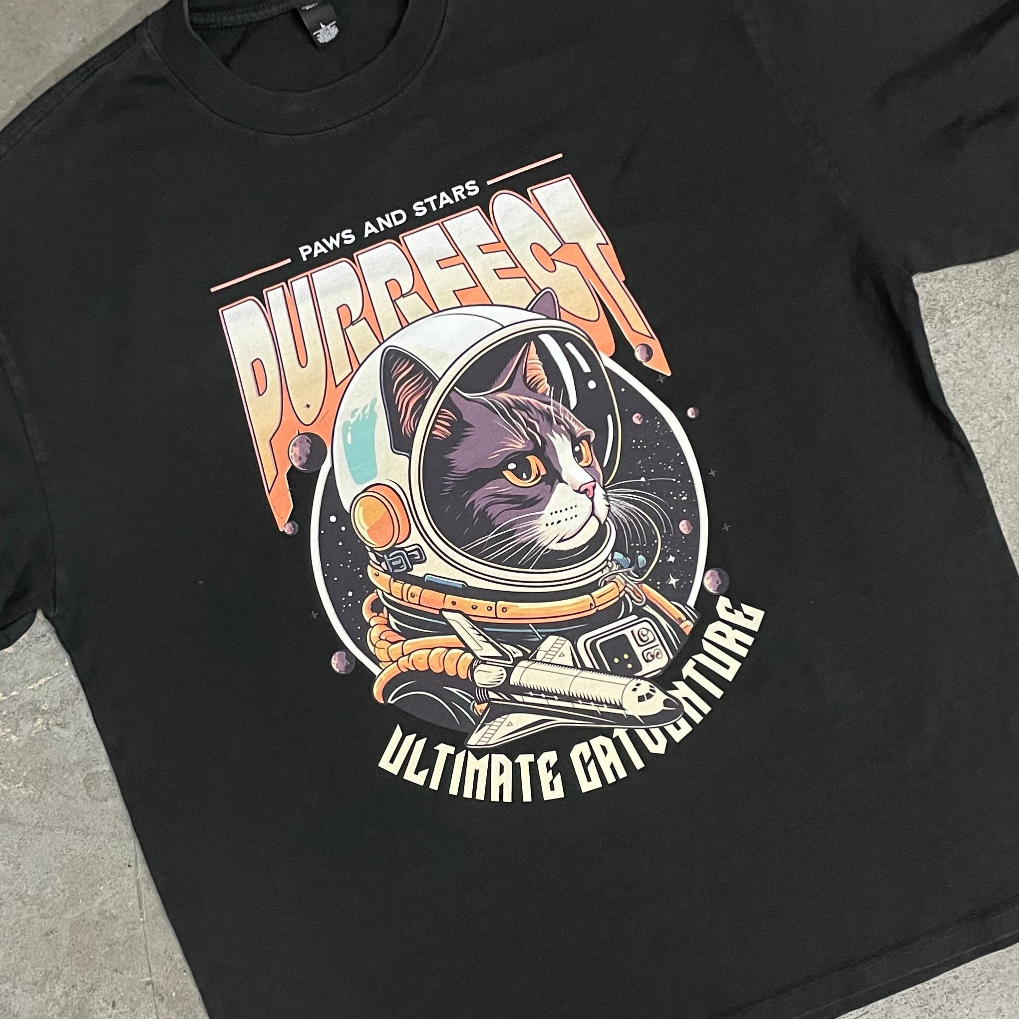 Black t-shirt with graphic design on a concrete surface